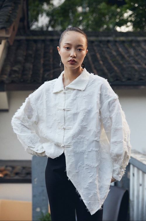 Person wearing a textured white jacket with a blurred background