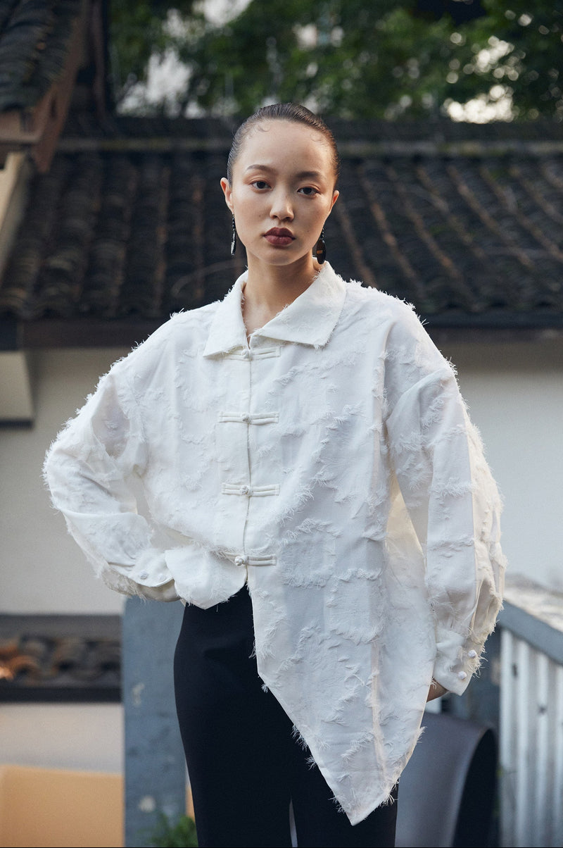 Person wearing a textured white jacket with a blurred background