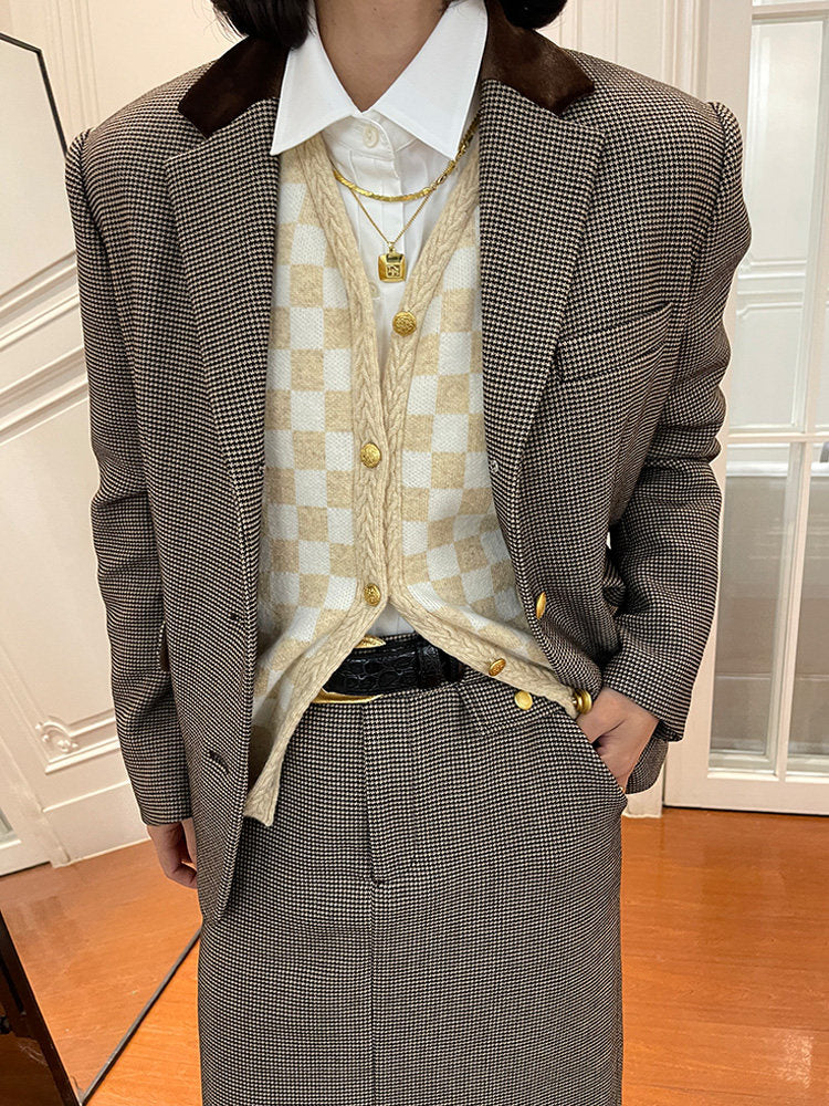 woman wearing a grey checkered suit with a white shirt and beige checkered vest.