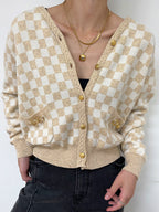 Beige and white checkered cardigan worn by a person on a white background