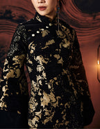An upclose shot of a woman standing against a textured wall, wearing a short, jacquard cheongsam dress with a stand collar neckline and full sleeves.