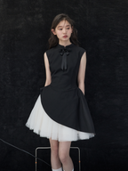 Woman wearing a black dress with a white skirt against a dark background