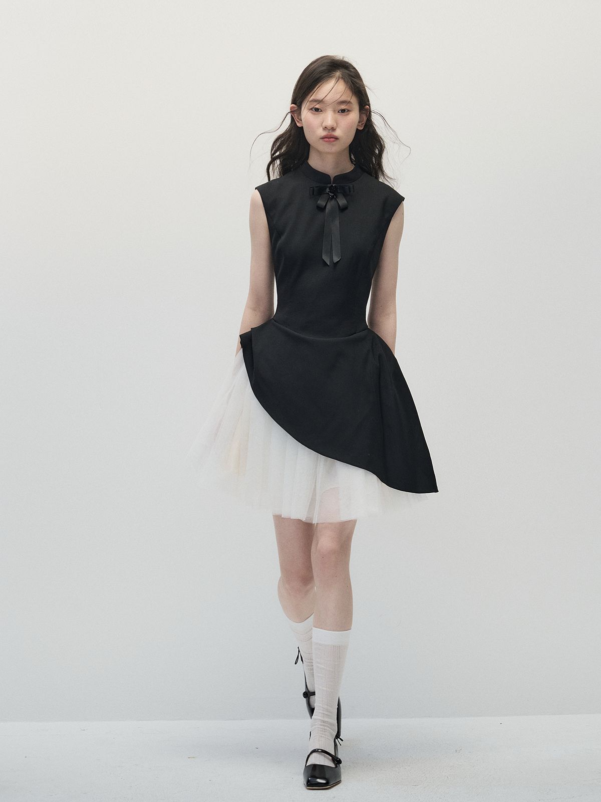 Woman wearing a black sleeveless dress with a white background