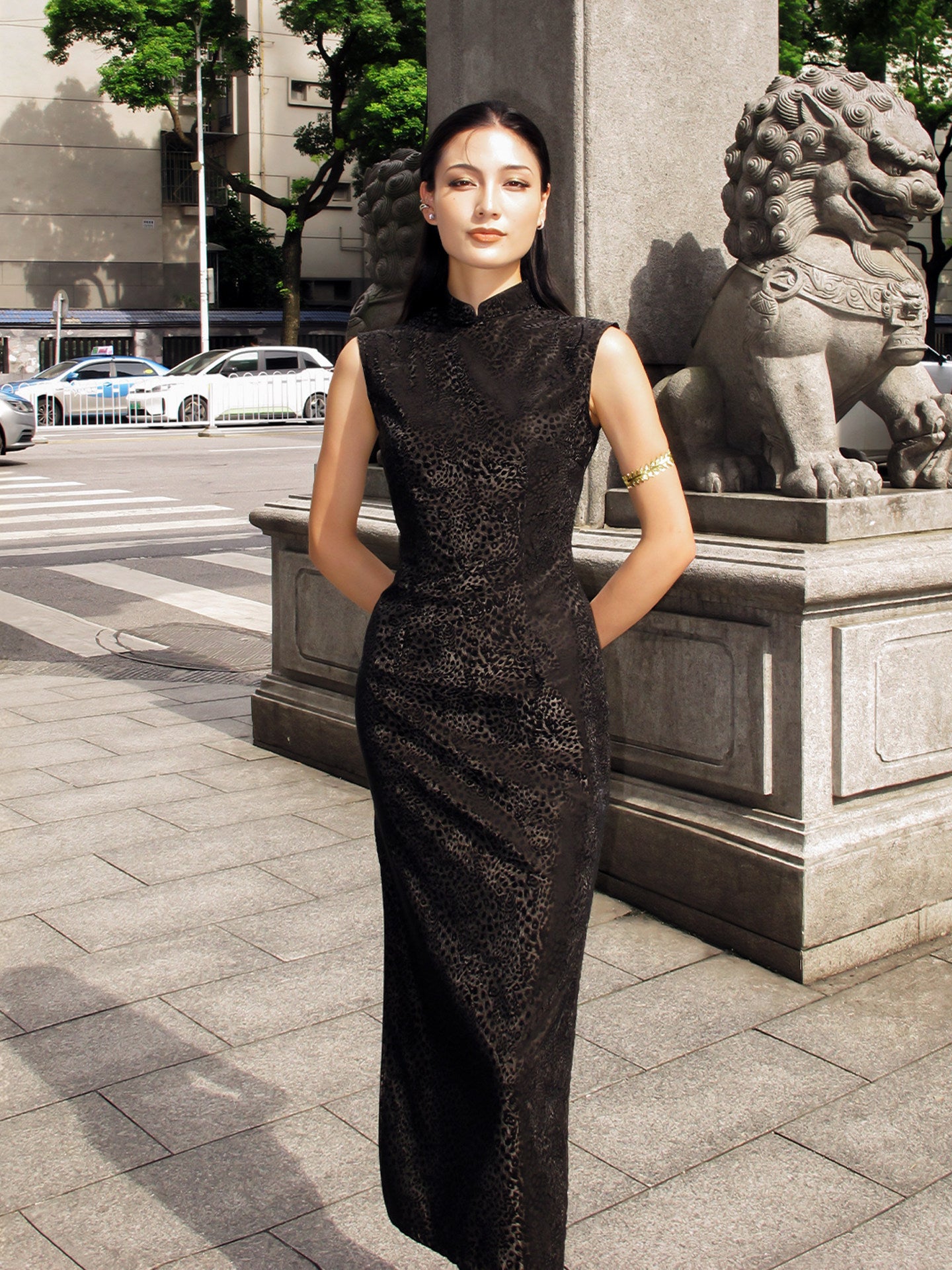 Woman in a black dress standing in an urban setting with stone lions.
