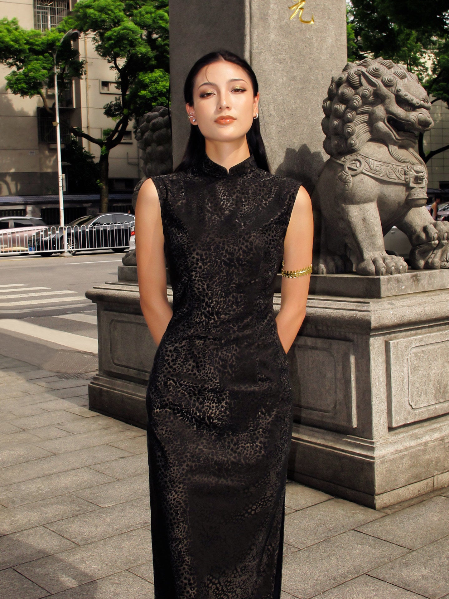 Woman in a black dress standing in an urban setting with stone lions.