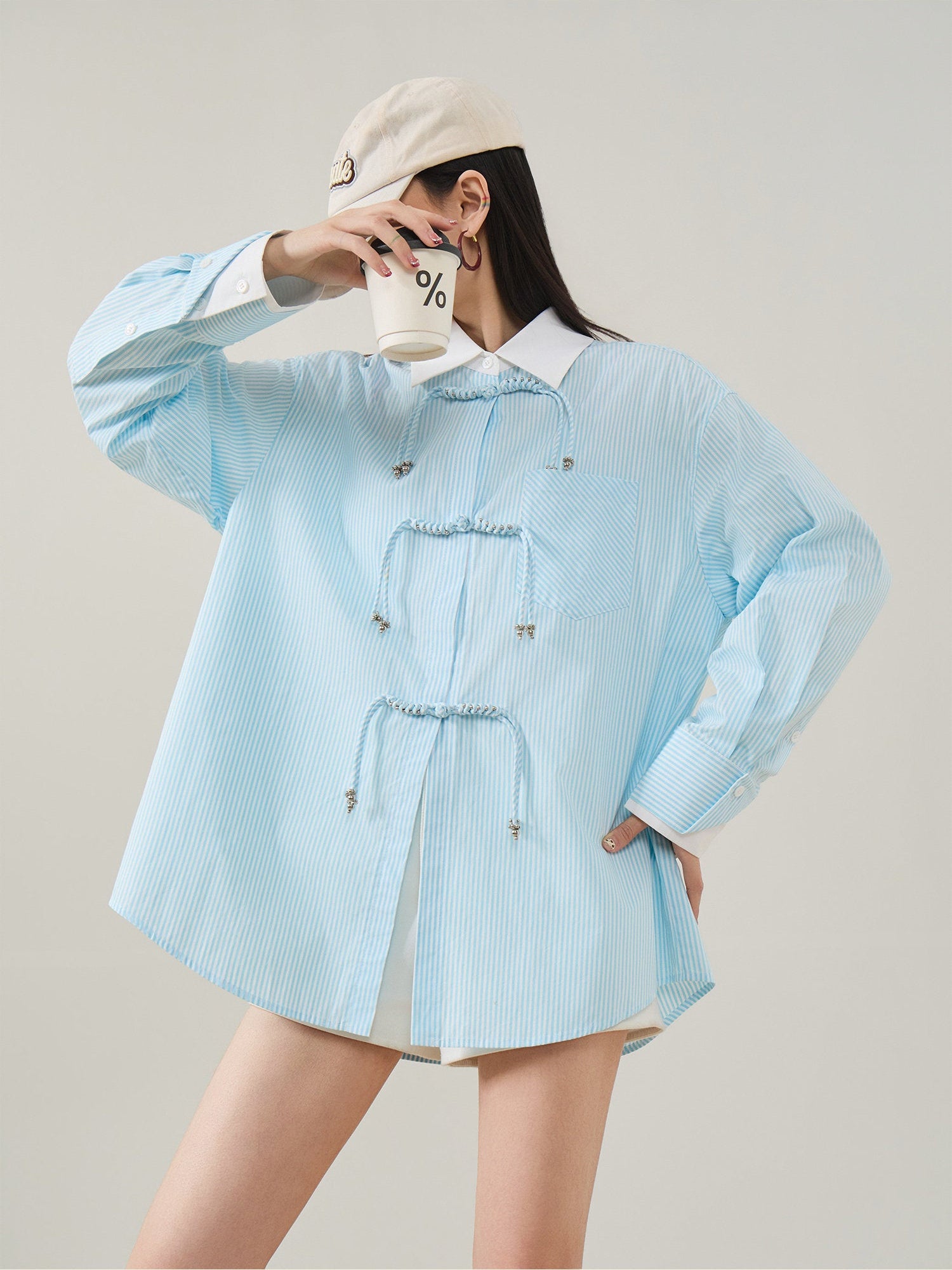 Person wearing a light blue checkered shirt with a white collar against a plain background