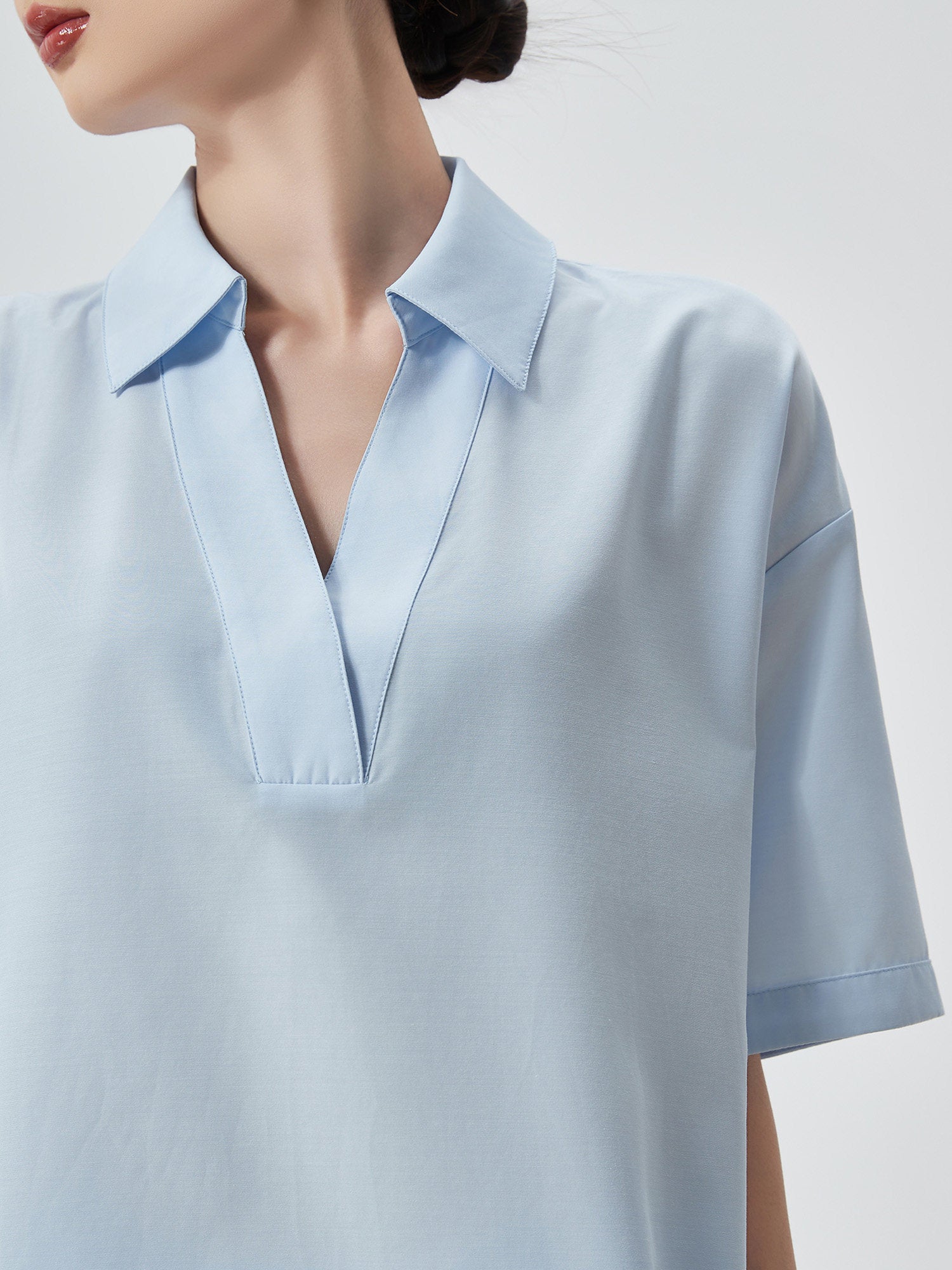Light blue blouse with a V-neckline on a neutral background