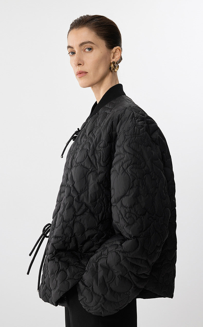 Person wearing a black quilted jacket on a white background