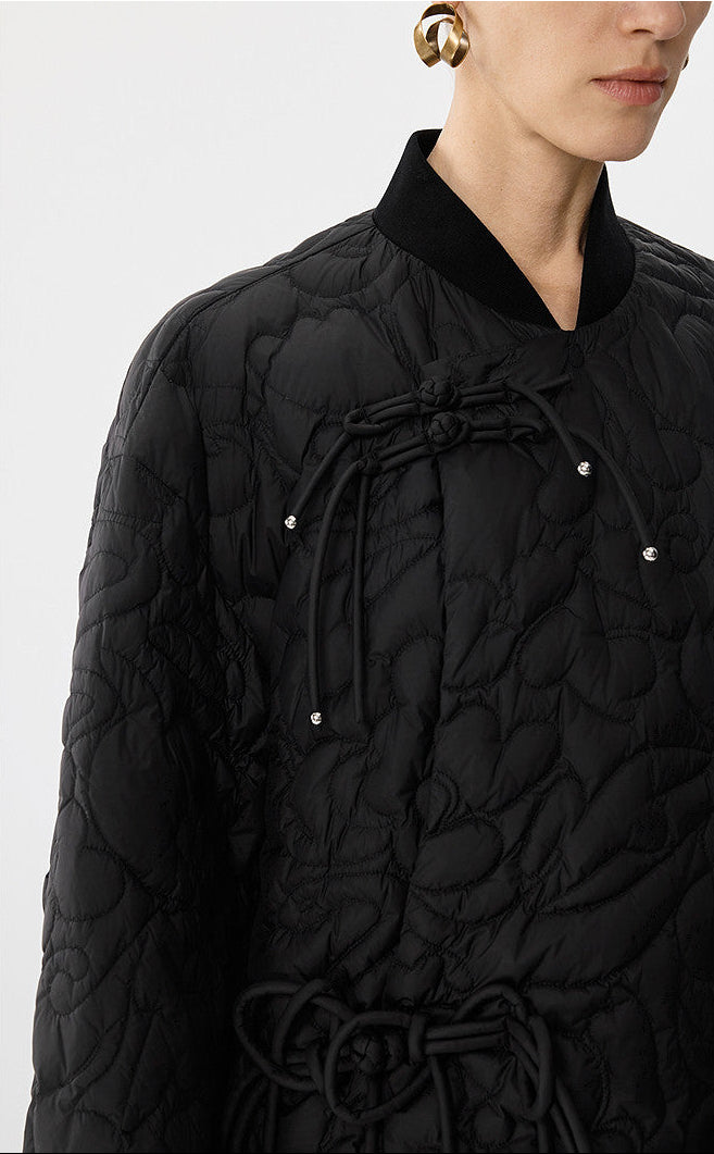 Black quilted jacket with a textured pattern on a white background