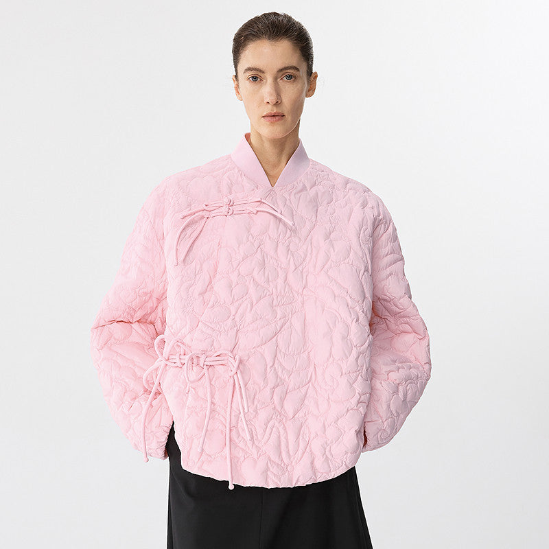 Person wearing a pink quilted jacket on a light gray background
