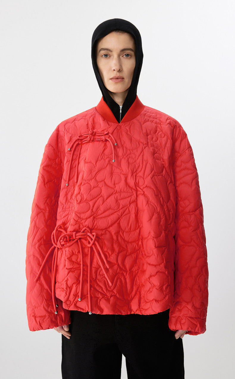 Person wearing a red quilted jacket with a black hood on a white background