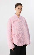 Woman wearing a pink quilted jacket on a white background
