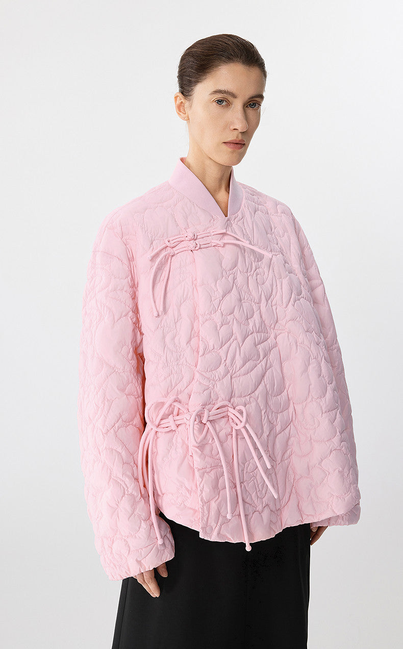 Woman wearing a pink quilted jacket on a white background