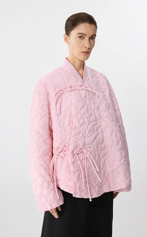 Woman wearing a pink quilted jacket on a white background