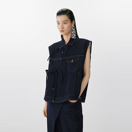 Person wearing a dark denim vest on a white background