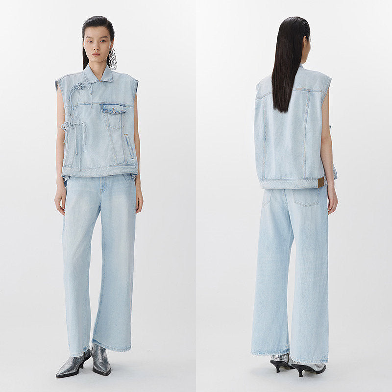 Woman wearing a light blue denim vest and pants, standing against a white background.