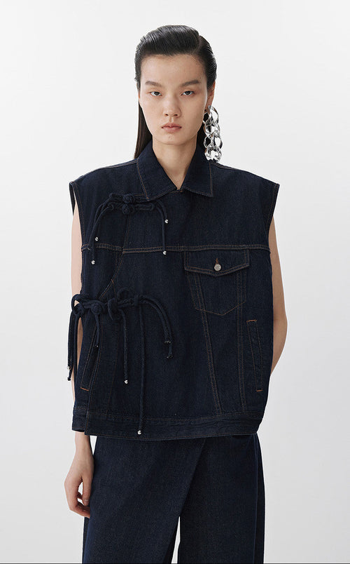 Person wearing a dark denim vest on a white background