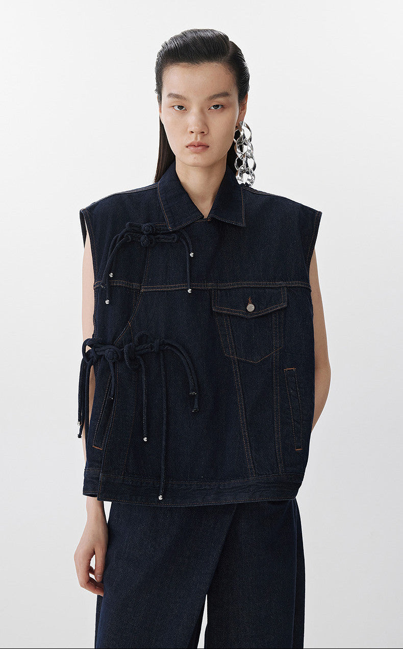 Person wearing a dark denim vest on a white background