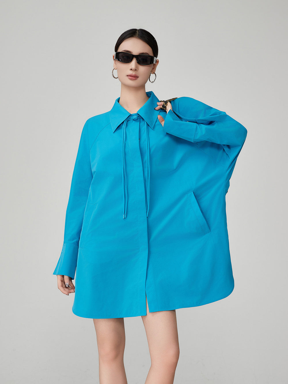 Woman wearing a bright blue dress with a collar on a gray background