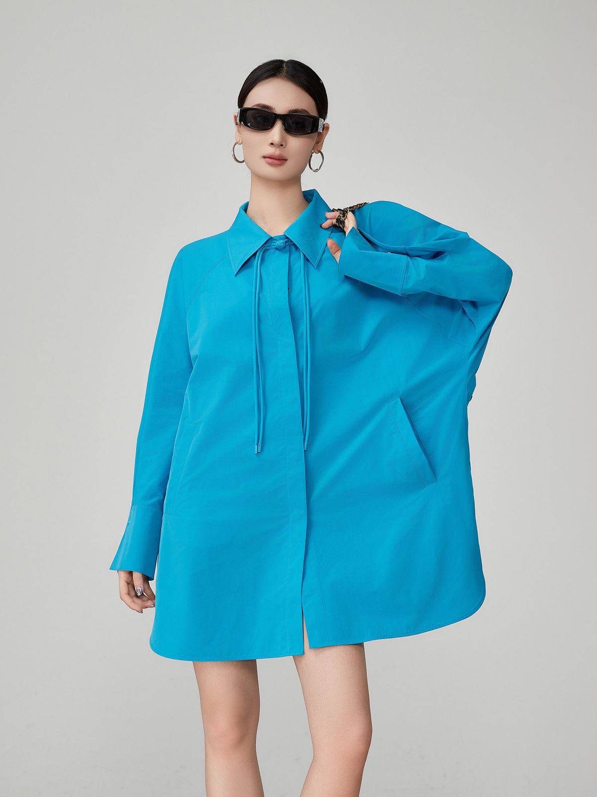 Woman wearing a bright blue dress with a collar on a gray background