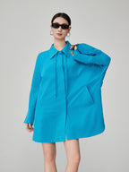 Woman wearing a bright blue dress with a collar on a gray background