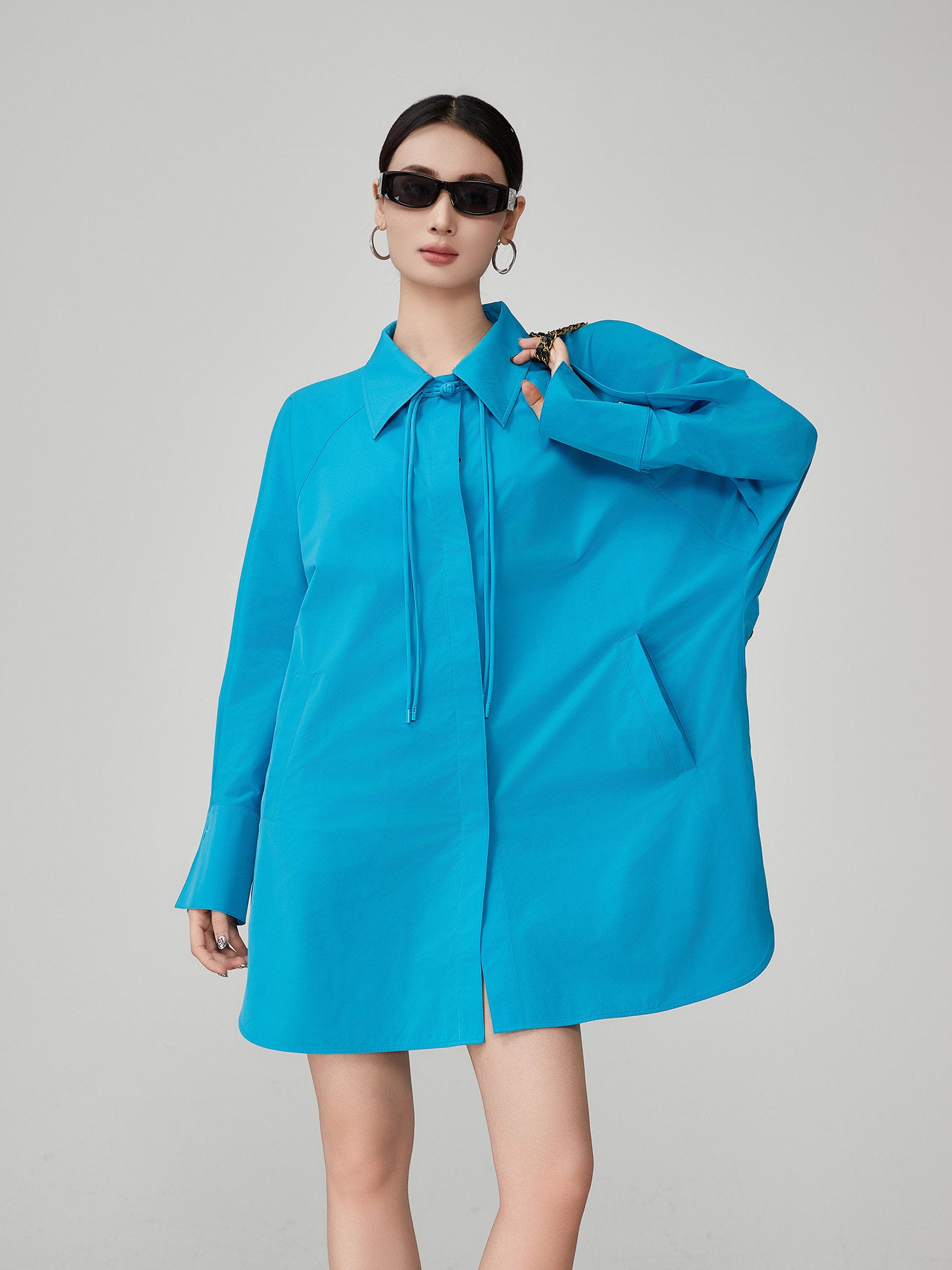 Woman wearing a bright blue dress with a collar on a gray background