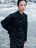 woman standing wearing a velvet suit jacket against a grey background. 