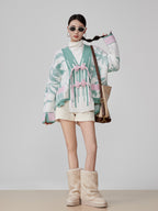 Woman wearing a patterned cardigan, white turtleneck, shorts, and beige boots on a plain background