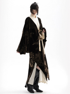 Person wearing a long, dark brown textured coat with a white shirt underneath on a white background