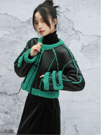 Person wearing a black outfit with green textured accents against a gray marble background