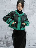 Person wearing a black and green textured jacket against a gray textured wall.