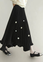 Black pleated skirt with white polka dots worn by a person on a plain background