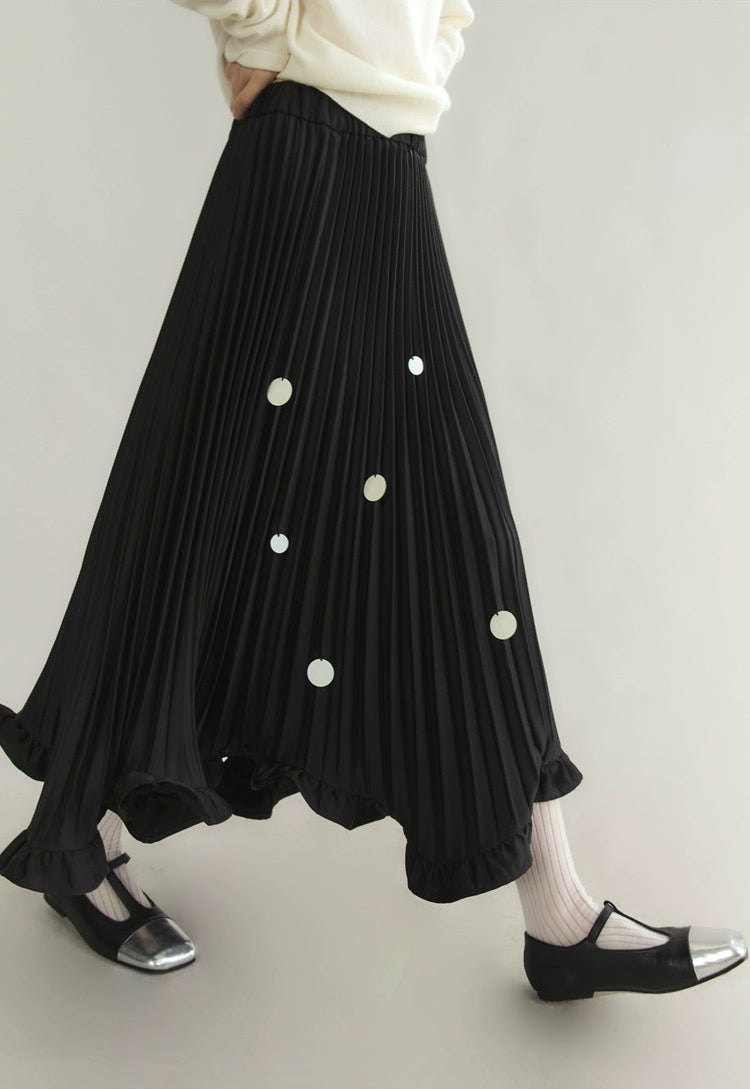 Black pleated skirt with white polka dots worn by a person on a plain background