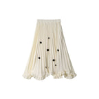 White pleated skirt with black button details on a white background