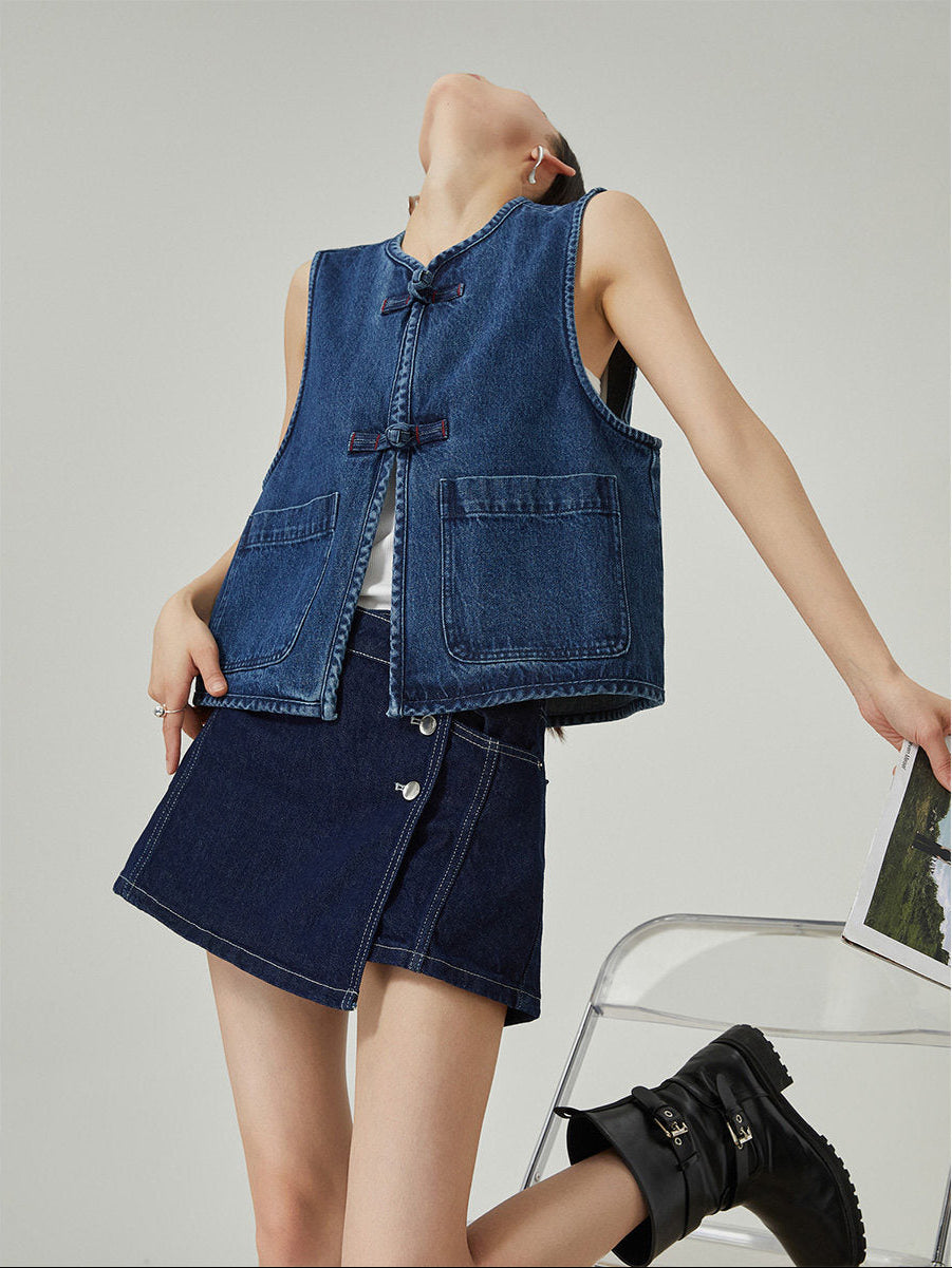 Woman wearing a denim vest and skirt set on a plain background