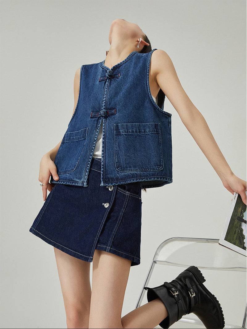Woman wearing a denim vest and skirt set on a plain background