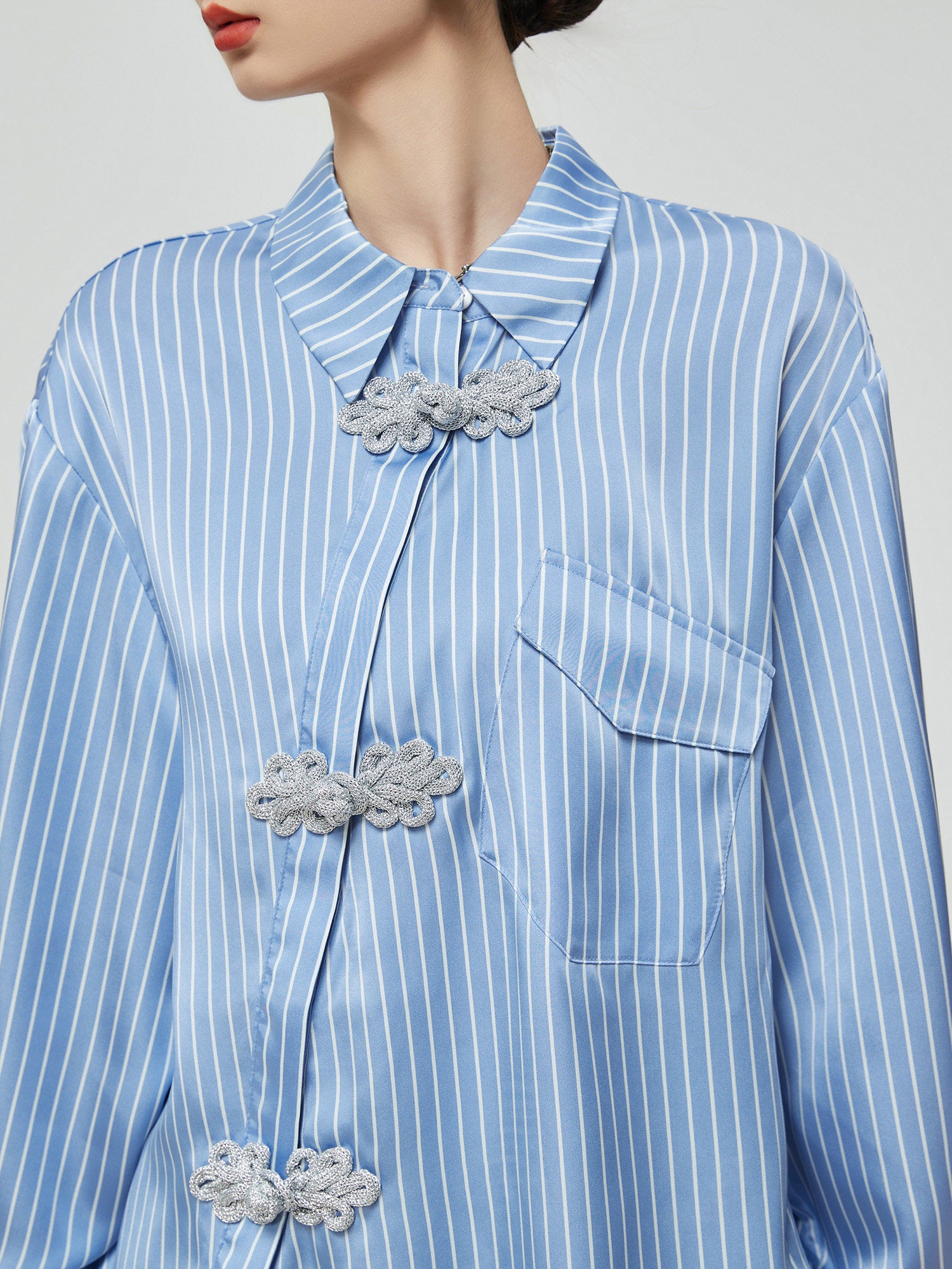 Close-up of a blue and white striped shirt with decorative cloud patterns on buttons.