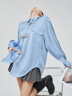 woman wearing a blue striped shirt with floral details on a white background