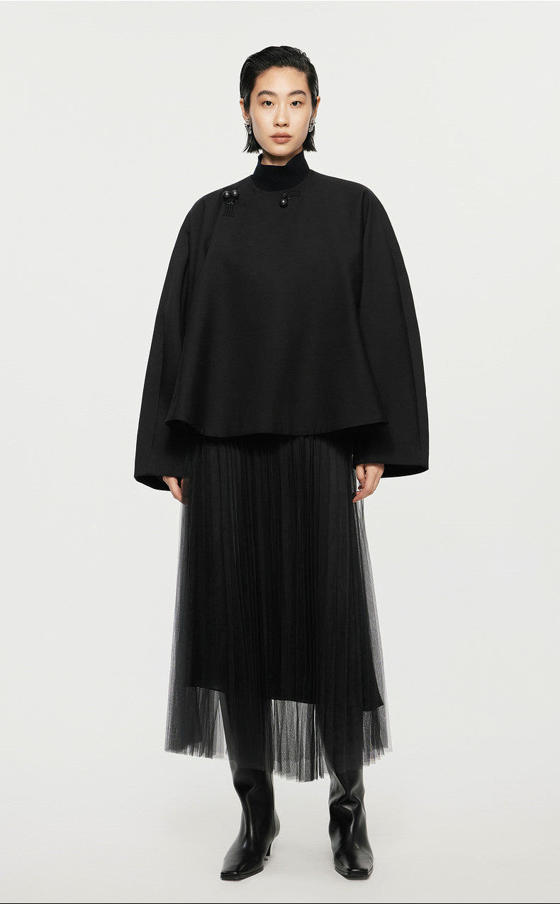 Person wearing a black outfit with a turtleneck and pleated skirt on a white background