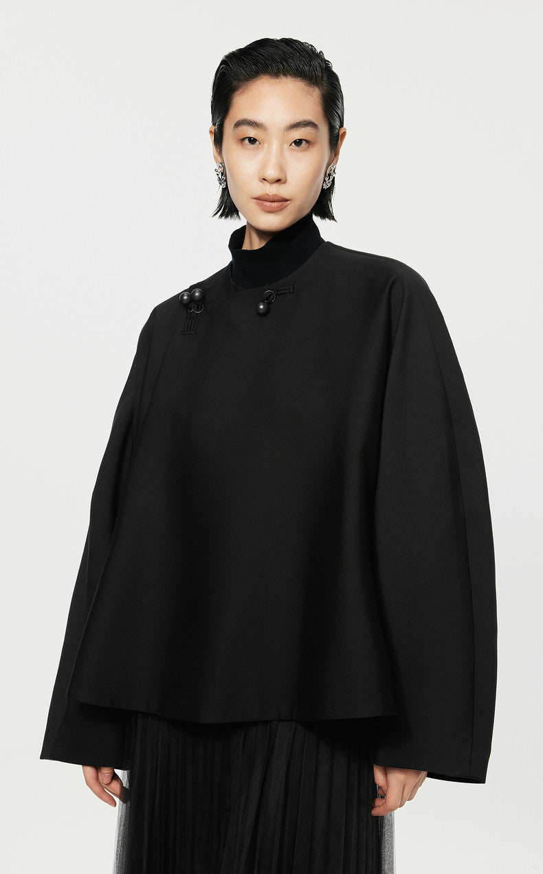 Person wearing a black coat against a white background
