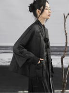Person wearing a black outfit with floral details in a minimalistic setting
