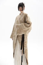 Person wearing a beige kimono-style garment on a white background