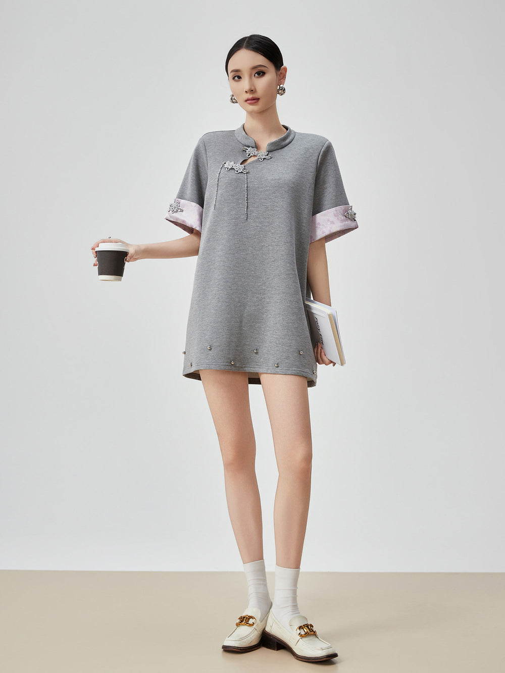 Woman wearing a gray dress with white accents on a plain background