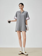 Woman wearing a gray dress with white accents on a plain background