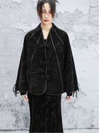 Person wearing a black textured outfit against a gray textured wall