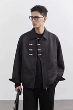 Man wearing a dark jacket with silver buttons against a white background