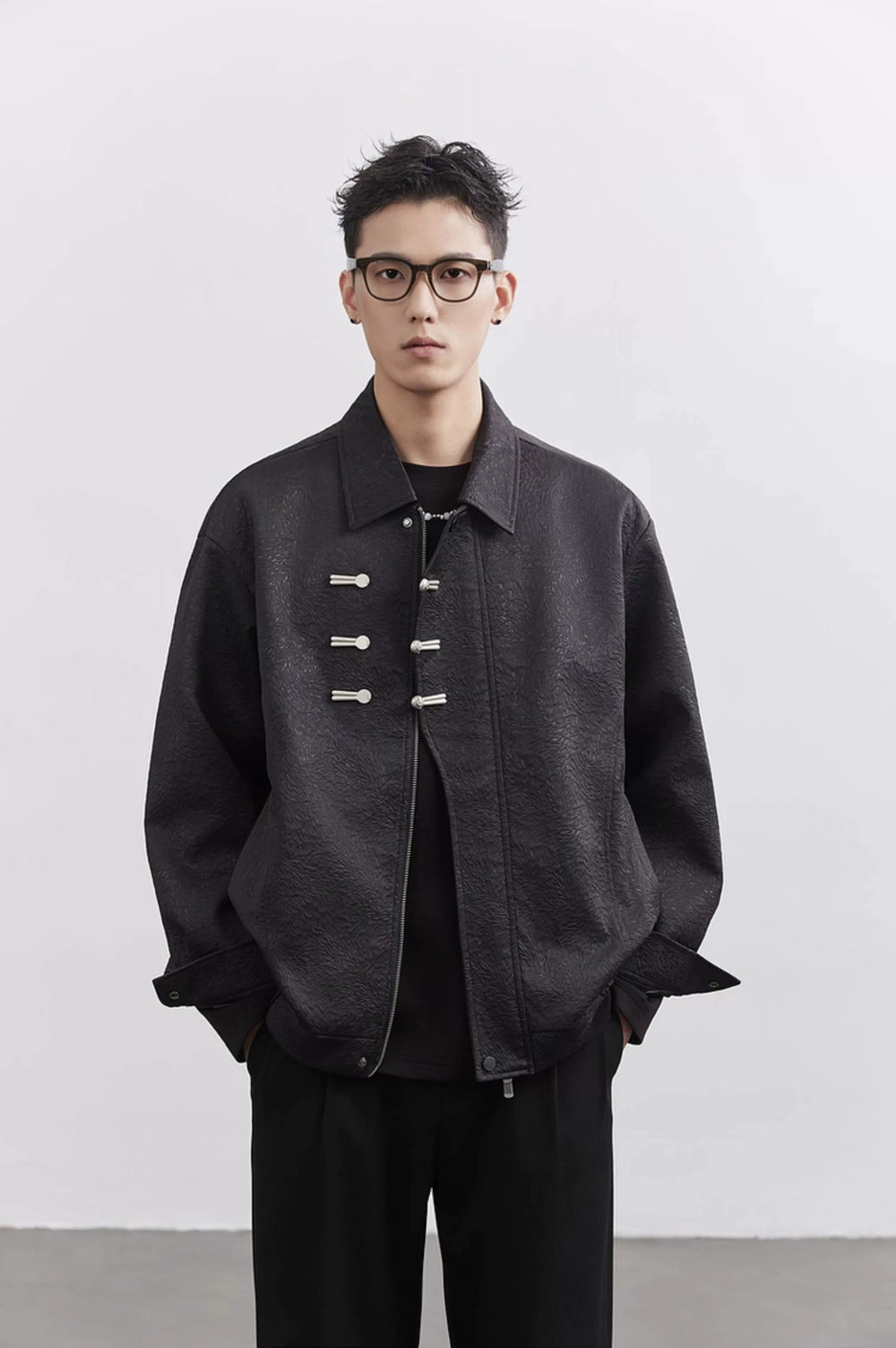 Person wearing a dark jacket with button details on a white background