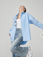 woman wearing a light blue shirt and jeans on a gray background