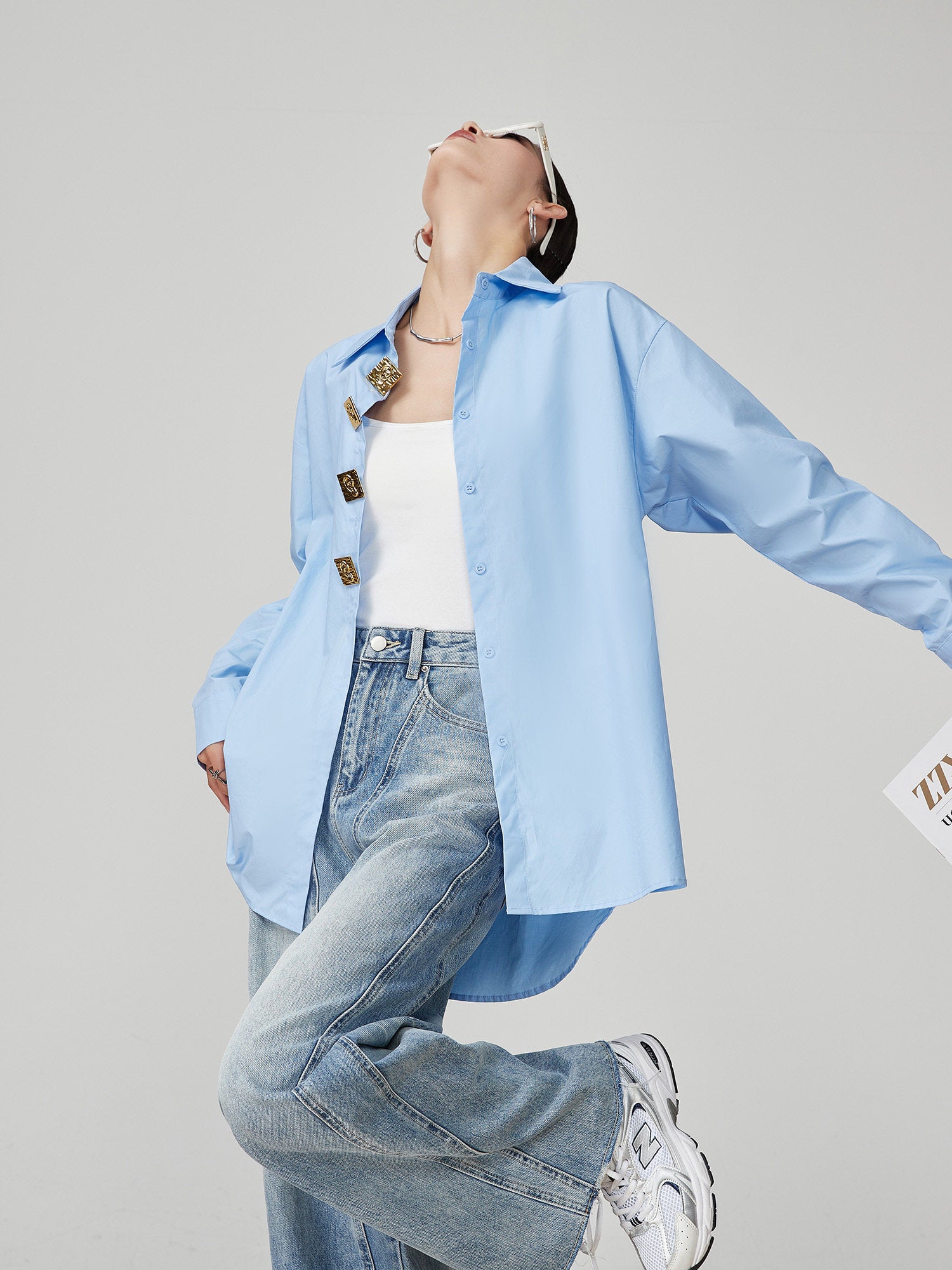 woman wearing a light blue shirt and jeans on a gray background