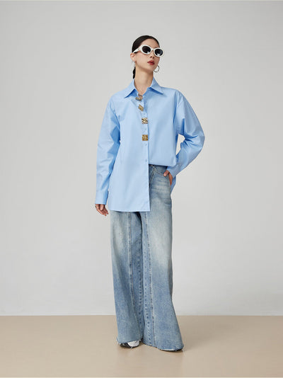 Person wearing a light blue shirt and wide-leg jeans on a plain background